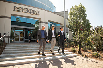 three men walking down the stairs talking in front of the Pepperdine Calabasas campus 