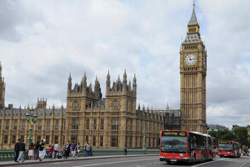 a street in London with a red bus and Parliament in the background