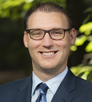 A headshot of Jacob Charles in front of a green background.